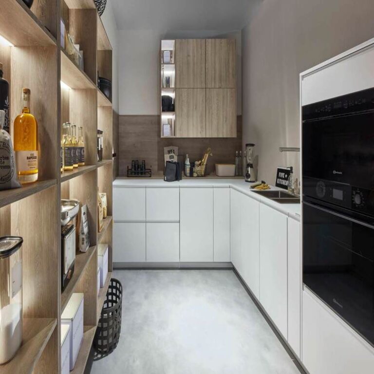 Moderne weiße Küche mit Hochschränken, Holzregal und schwarzen Einbaugeräten – Küche kaufen Karlsruhe